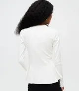 Blusa de punto roma color blanco, con cuello redondo, mangas largas y diseño peplum con ruedo amplio y estructurado.