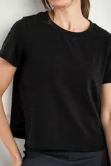 Remera negra de manga corta con cuello redondo y textura de líneas horizontales y pequeños puntos calados. Tiene un corte ajustado al cuerpo.