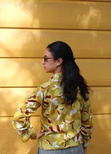 Blusa verde de manga larga con cuello tipo lazo, confeccionada en tela con textura ligera y corte recto.