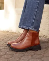 Botas tipo chelsea de cuero color marrón óxido, con paneles laterales de textura combinada y suela track negra de goma.