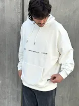 Canguro blanco con capucha ajustable con cordones, bolsillo tipo canguro y logo estampado en el pecho.