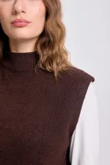 Chaleco de punto en color marrón, con cuello alto y diseño sin mangas. Presenta un tejido de punto liso y corte holgado.