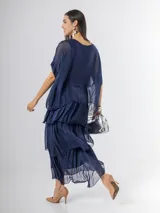 Vestido largo azul marino de seda italiana, con diseño de volados escalonados en la falda y una sobrecapa superior con mangas cortas amplias.