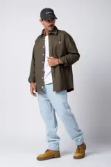 Camisa de manga larga estilo sobrecamisa, color negro, con corte oversize, cuello clásico, cierre frontal con botones y bolsillo frontal en el pecho.