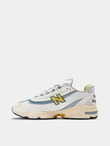 Championes New Balance modelo 1000, color blanco hueso con detalles en celeste y amarillo.