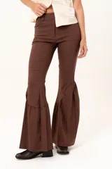 Pantalón de corte ajustado en la parte superior y pierna acampanada con volados en el ruedo. Presenta cierre frontal y bolsillos laterales.