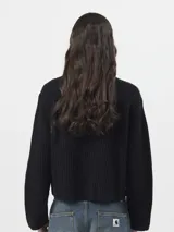 Sweater de punto acanalado color negro, con cuello redondo, mangas largas y un bolsillo frontal en el pecho con etiqueta de la marca.