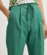 Pantalón de corte fluido y cintura media con cordón ajustable. Presenta diseño liso con bolsillos laterales y confección en tejido de viscolino.