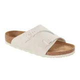 Sandalia tipo slide en color blanco, con doble tira ajustable con hebillas y base de corcho natural con suela de goma.