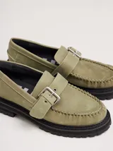 Mocasines color cuero, confeccionados en cuero, con suela track negra y detalle de hebilla metálica plateada.