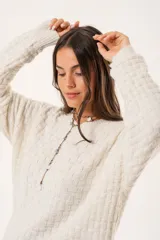 Buzo oversize color beige confeccionado en tejido sintético con destellos de lurex, cuello redondo y manga larga.