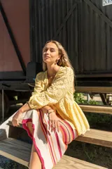 Camisa amarilla de broderie con escote en V, mangas globo y lazos ajustables en el frente.