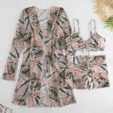 Conjunto de traje de baño de tres piezas con estampado de hojas tropicales en tonos blanco y negro. Incluye un top tipo tankini con cordón ajustable en el centro, un short de tiro alto y una camisa abierta de manga larga tipo salida de baño.