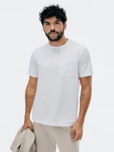 Camiseta blanca de manga corta con cuello redondo y un bolsillo de parche en el lado izquierdo del pecho.