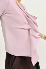 Top de punto rosado con escote en V y manga corta, decorado con un volante asimétrico en la parte delantera.