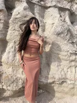 Conjunto de dos piezas compuesto por un top de escote recto y una falda larga de corte ajustado, confeccionados en tela bambula elastizada de textura arrugada.