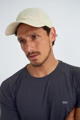 Gorro deportivo color beige con perforaciones y visera curva.