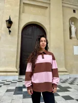 Buzo deportivo de corte holgado con diseño de rayas horizontales anchas en color marrón y rosado. Presenta cuello tipo polo con cierre frontal de botones y mangas largas con puños ajustados.