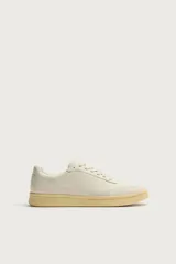 Zapatillas de piel estilo retro, color blanco crudo, con suela de goma con volumen en tono tostado y cierre de cordones.