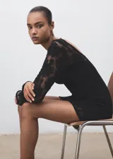 Vestido corto de crochet negro con cuello redondo y mangas largas acampanadas. Presenta una espalda abierta con cierre de lazo y cuenta con forro interior.