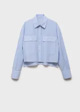 Camisa corta a rayas verticales celestes y blancas, de manga larga con puños abotonados, cuello camisero, cierre frontal con botones, y dos bolsillos de parche con solapa en el pecho.