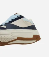 Championes casuales de estilo urbano con diseño de paneles en colores azul marino, beige y celeste. Presentan suela tipo caja de goma color crema con base marrón, cordones gruesos en color celeste y lengüeta acolchada.