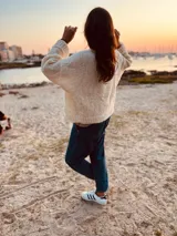 Sweater tejido en boucle color crema, de corte holgado y mangas largas.