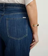 Pantalón de jean modelo wide leg, de tiro medio y corte amplio desde la cadera hasta el ruedo. Presenta cierre frontal con botón, bolsillos laterales y traseros, y trabillas en la cintura.