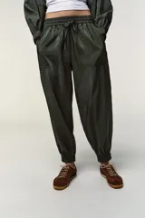 Pantalón negro de tiro medio con acabado brillante, cintura elástica ajustable con cordones y puños elásticos en los tobillos.