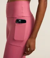 Calza deportiva larga color rosa con cintura alta, bolsillos laterales y franjas blancas en los laterales.
