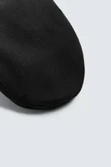 Boina de estilo clásico con visera corta, confeccionada en tejido de lana color marrón oscuro.