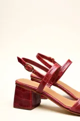 Sandalia de cuero vacuno color negro con textura de cocodrilo, taco cuadrado de 4 cm, punta cuadrada y dos tiras finas, una en el empeine y otra con hebilla en el tobillo.