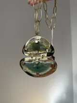 Collar de cadena de eslabones dorados con un dije doble compuesto por dos piezas de piedra ágata en tonos verdes engarzadas en metal dorado.
