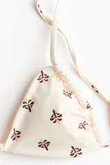Top de bikini triangular color beige con estampado de pequeños motivos florales marrones y rosados, breteles ajustables y tiras para anudar en la espalda.