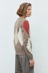 Sweater de punto con diseño de rombos en tonos tostado, beige y blanco, con detalles en color terracota en las mangas. Presenta cuello redondo y puños acanalados.