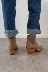 Bota corta de cuero gamuzado color negro, con punta fina y diseño bordado estilo western. Tiene un pequeño tirador en la parte trasera y un taco cónico de altura media.