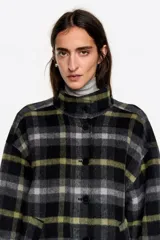 Abrigo midi de estructura envolvente confeccionado en mezcla de lana doble faz. Presenta cuello subido, cierre frontal con botones, mangas largas amplias con ajuste de botón en el puño y bolsillos laterales de vivo.