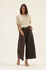 Blusa color beige de raso con ribete de lurex y mangas cortas.