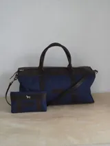 Bolso de lona color verde militar con detalles en cuero marrón. Tiene doble asa de mano y correa de hombro ajustable y extraíble.