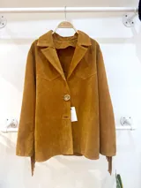 Blazer de gamuza color maíz, con cuello solapa, cierre con botón y flecos en las mangas.