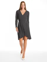 Vestido envolvente de seda fría con estampado de lunares, escote en V cruzado, manga larga y cintura elastizada con aplique metálico lateral. Presenta un ruedo asimétrico en el frente.