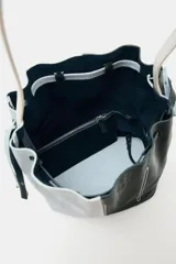 Bolso de hombro de piel con diseño bicolor en celeste y negro. Cuenta con cierre fruncido y pespuntes decorativos.