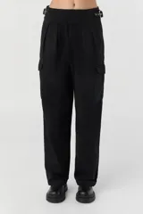 Pantalón cargo negro de corte slouchy y fit amplio, confeccionado en gabardina de algodón. Presenta un diseño de cintura cruzada con cinturón integrado ajustable mediante ojalillos metálicos y hebilla. Posee pliegues frontales y bolsillos cargo a los lados.