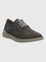 Sneaker de estilo oxford en tonos gris, confeccionada en gamuza con detalles perforados tipo brogue. Presenta cordones planos de cinta y una suela de plataforma en color gris claro.