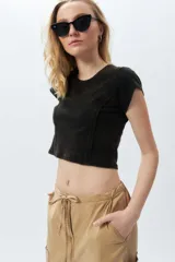 Top corto de manga corta, color negro con efecto desgastado o acid wash, cuello redondo y costuras verticales que definen la silueta.