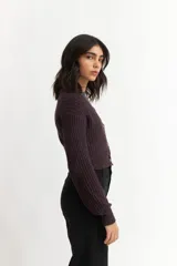 Cárdigan color borgoña de tejido de punto con textura acanalada, escote en V, cierre frontal con botones y mangas largas abullonadas.