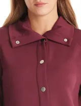 Campera bordó de modal con cuello solapa, cierre frontal con botones metálicos y bolsillos laterales. Presenta mangas largas con detalles labrados en los antebrazos y puños ajustados.