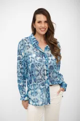 Camisa de manga larga con cuello clásico y cierre frontal de botones, confeccionada en tela liviana con estampado tipo tie-dye en tonos celestes y blancos.