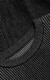 Sweater de cuello redondo con diseño de tejido acanalado vertical en color negro. Presenta detalles de costuras en contraste blanco en los hombros y en el ruedo, con un corte holgado y terminaciones en punto rib.