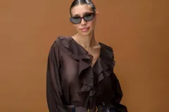 Camisa de color marrón con volados frontales, escote en V y mangas largas con puños ajustados.